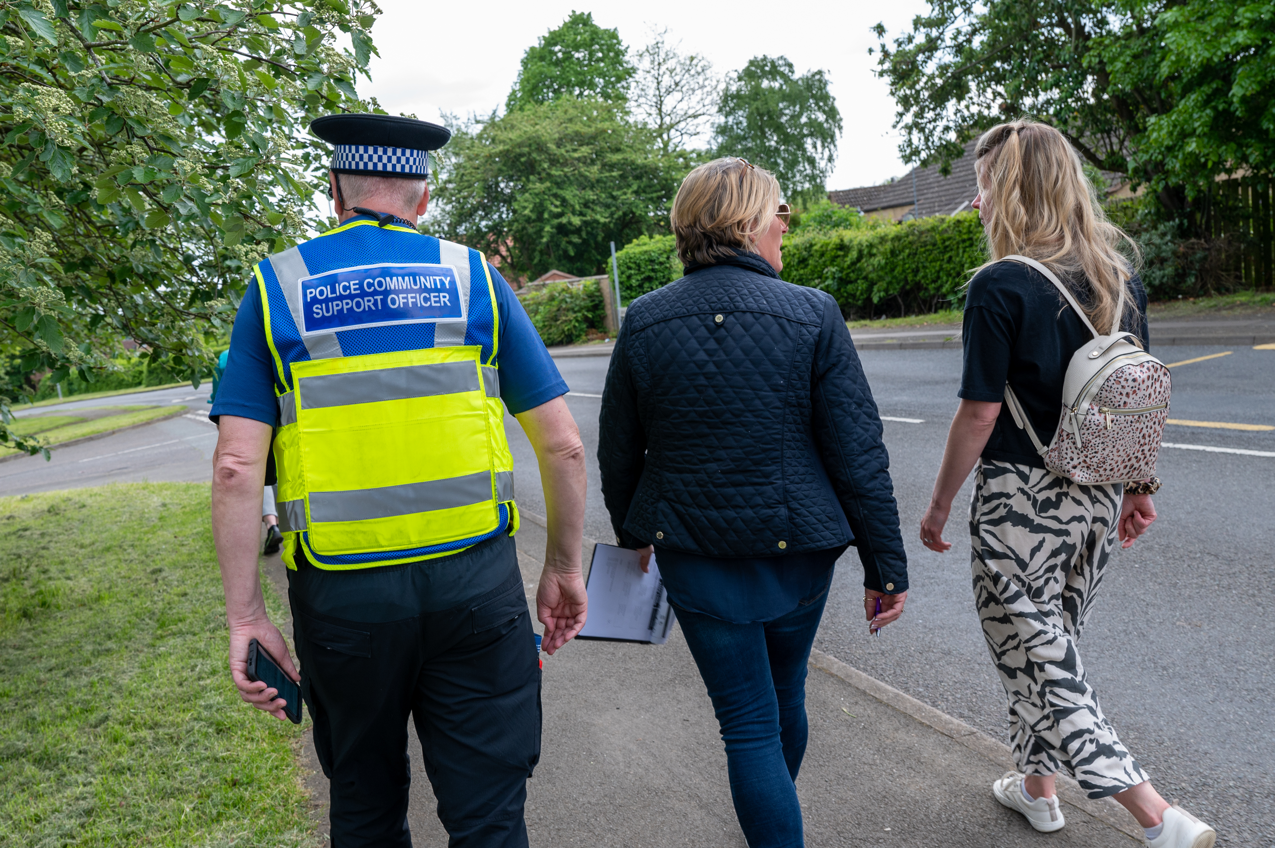 A Police Community Support Officer walking with two other adults