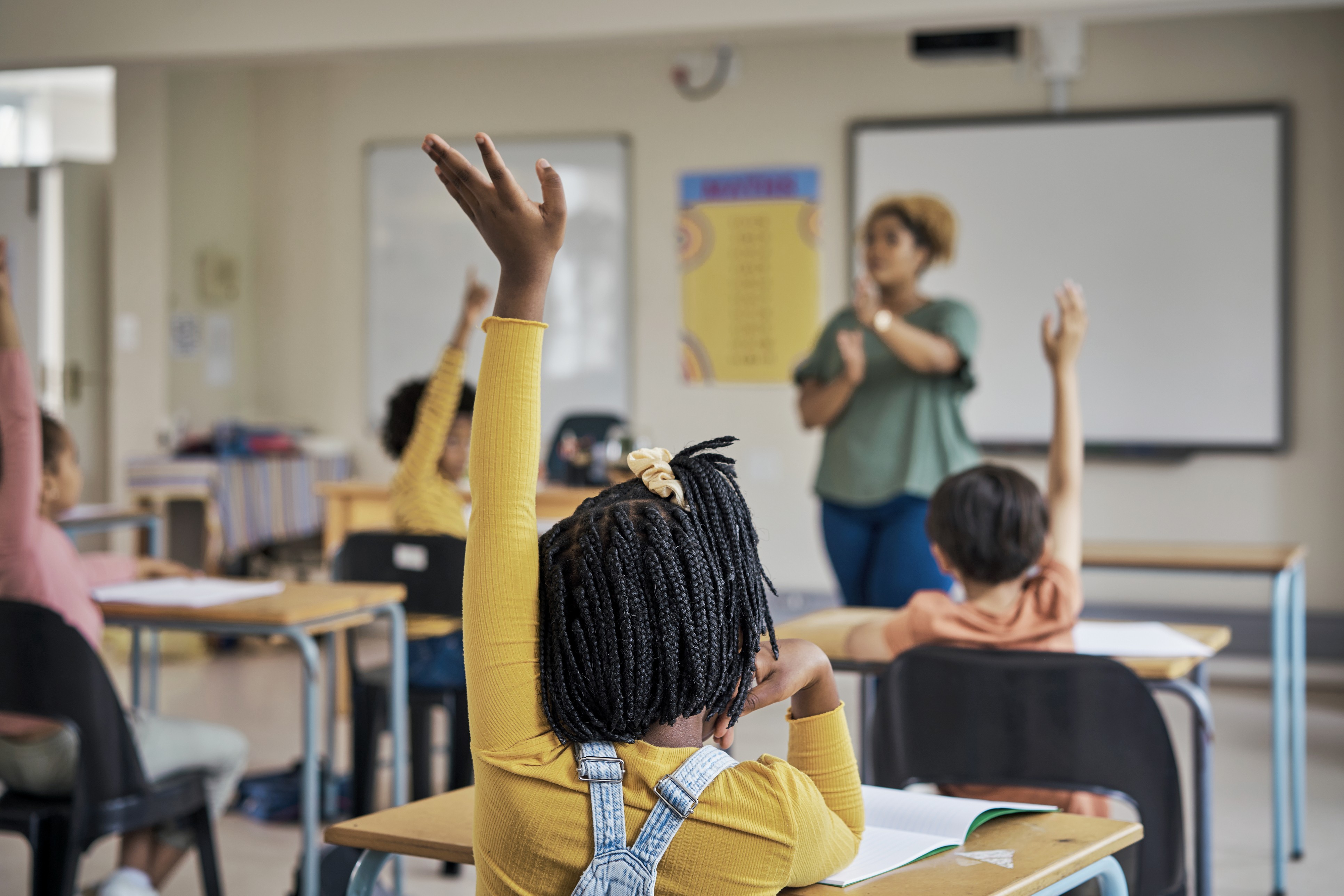 Pupils raising their hands in a classroom