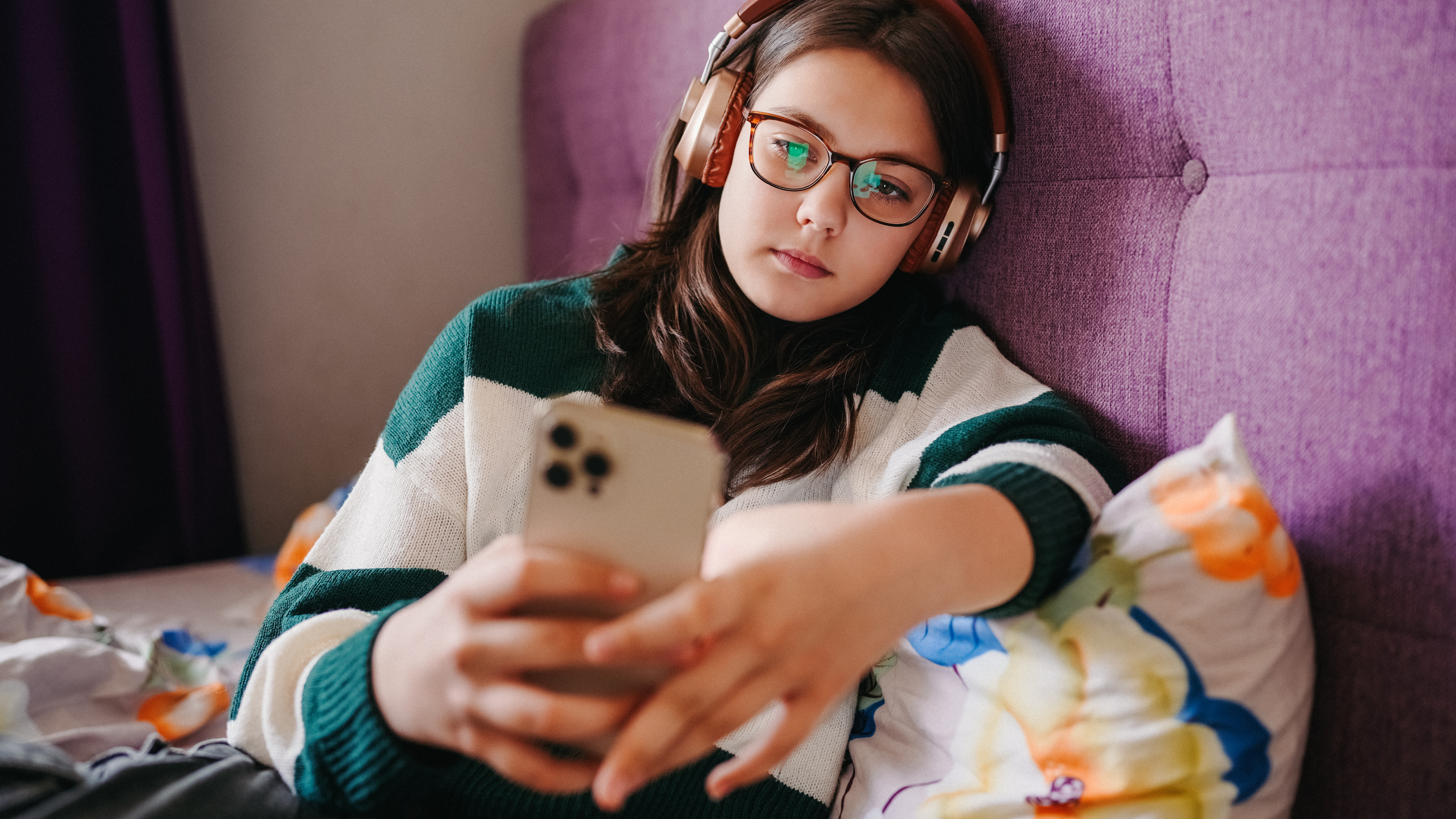 A young person wearing headphones looking at a smartphone